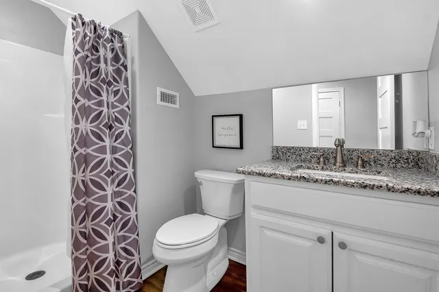 a bathroom with a granite countertop toilet sink and mirror
