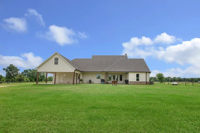 a view of a house with a big yard and large trees