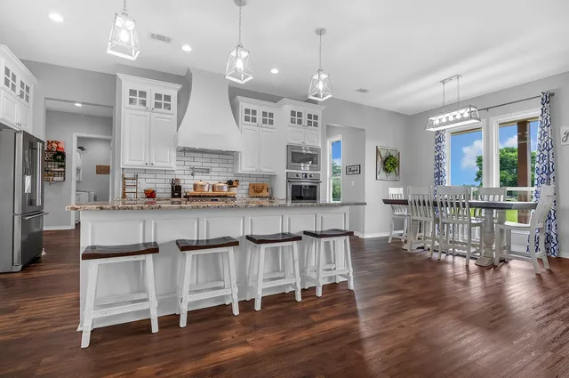 a open kitchen with stainless steel appliances granite countertop a stove refrigerator dining table and chairs