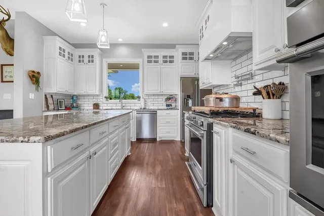 a large kitchen with stainless steel appliances granite countertop a lot of counter space and wooden floors