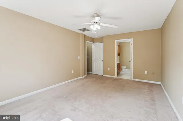 an empty room with a chandelier fan and closet