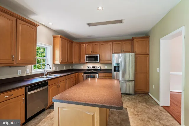 a kitchen with wooden cabinets sink and stainless steel appliances