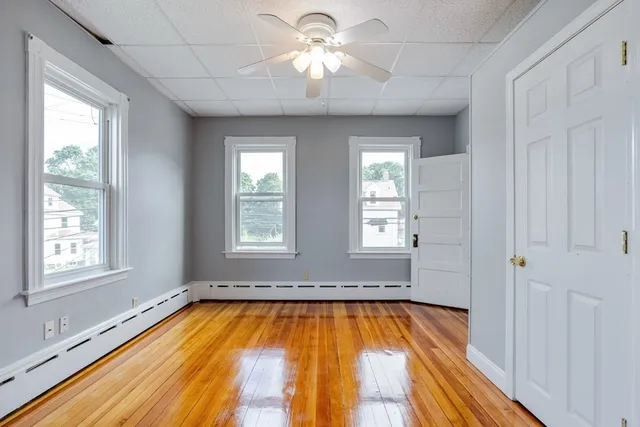 a view of a room with large windows and chandelier fan