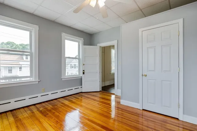 a view of empty room with wooden floor and fan