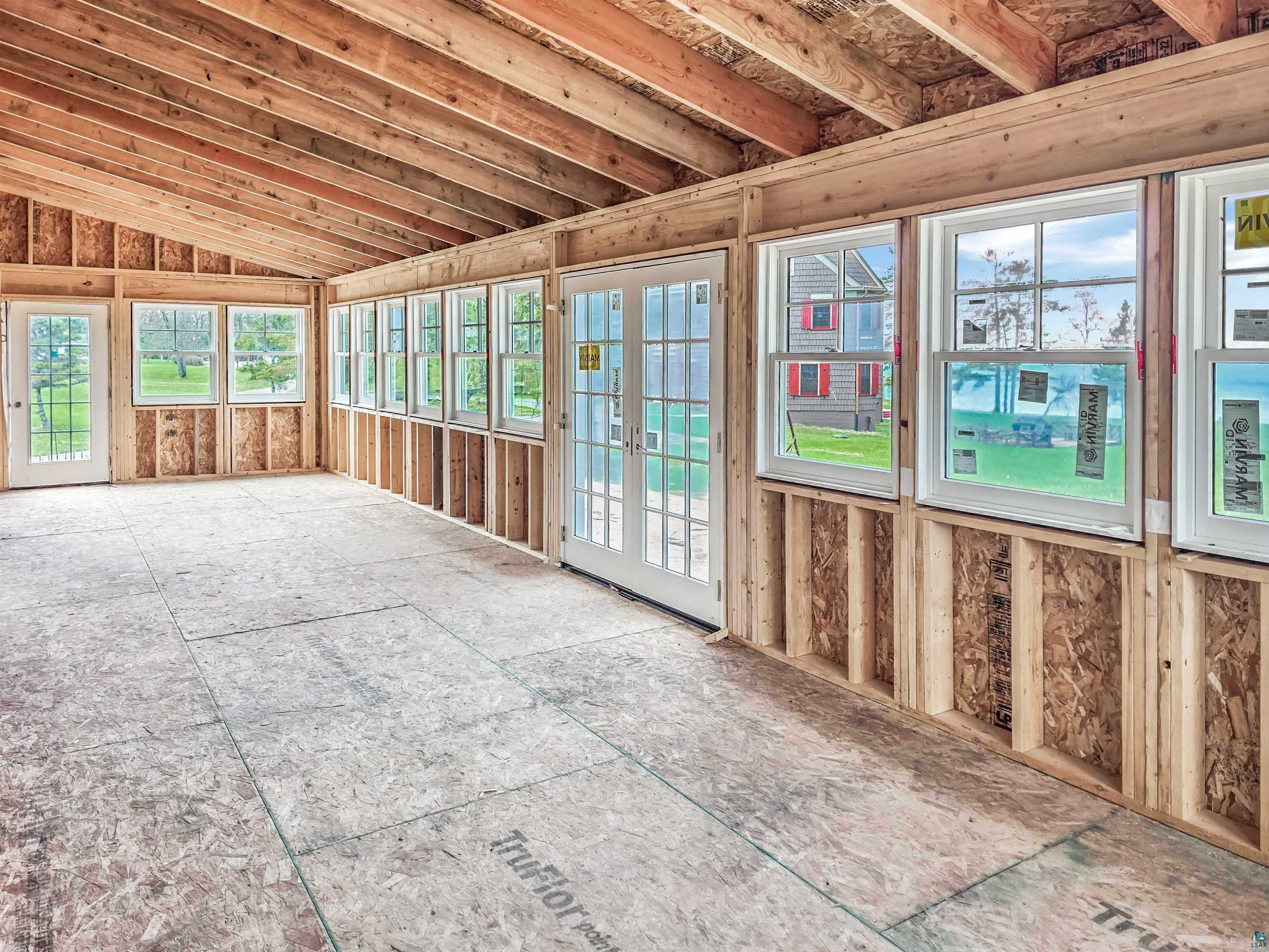939 Whitefish Street La Pointe, WI 54850 - Photo 21 of 30 Open concept space featuring exposed wood framing, multiple windows, double-pane glass French doors, and plywood subflooring