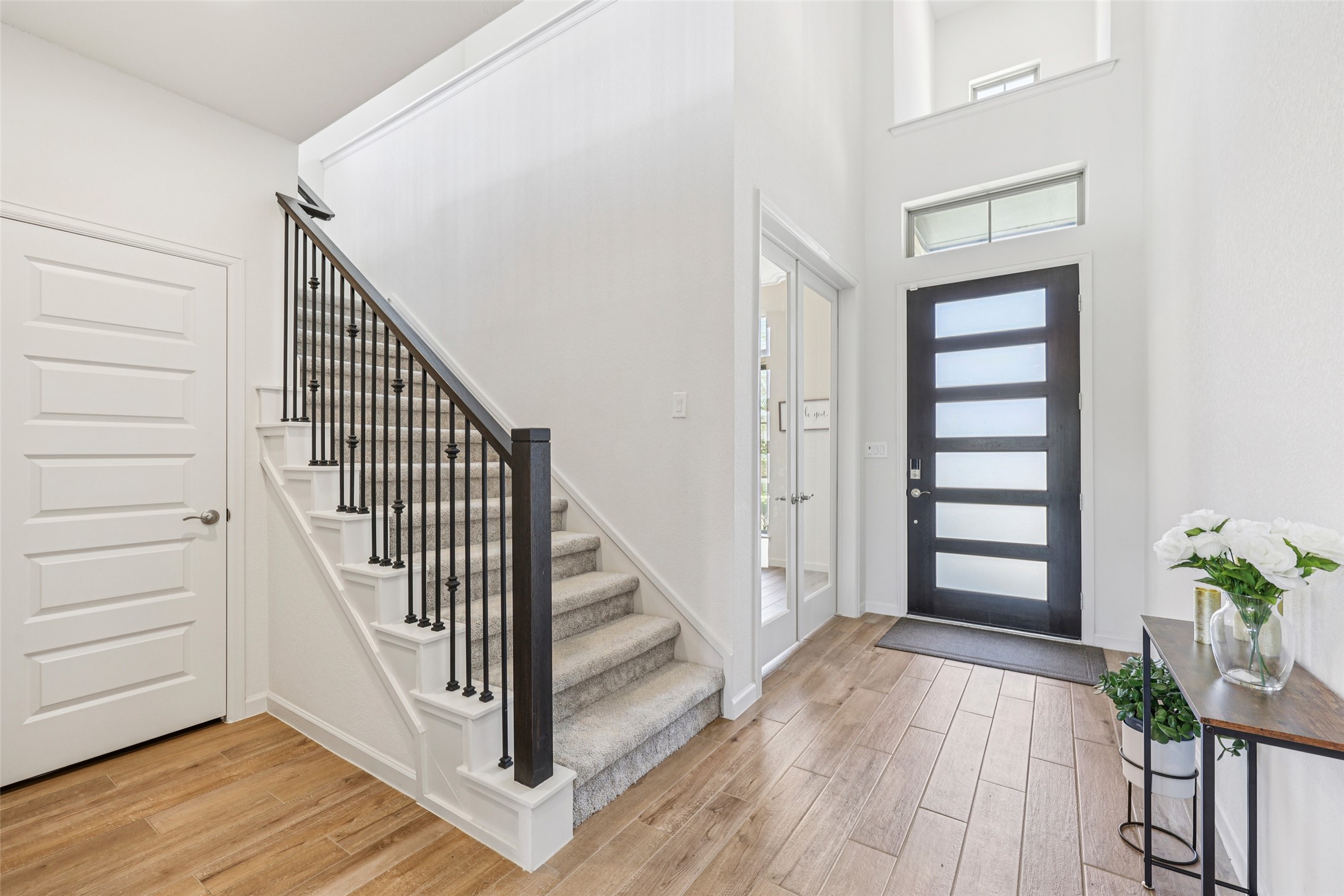 1140 Bryson Rdg Trail Leander, TX 78641 - Photo 24 of 39 The entryway features light-colored wood-look flooring, a carpeted staircase with dark iron balusters, and a modern dark-framed front door with frosted glass panels