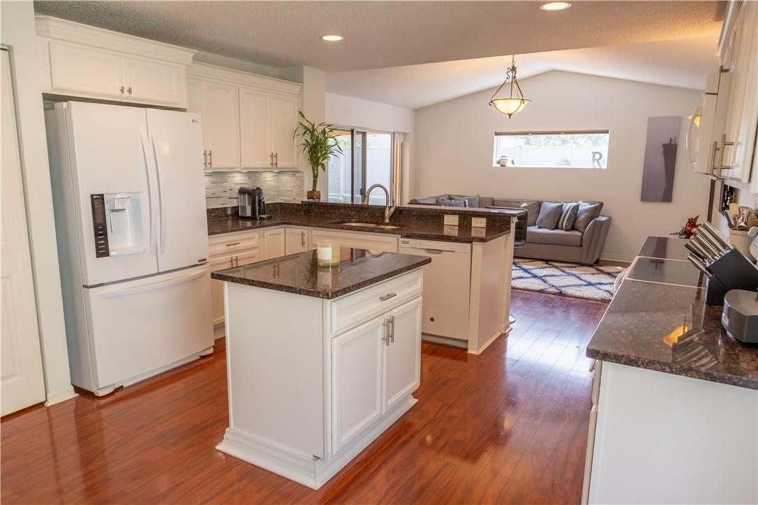108 West Lee Road Delray Beach, FL 33445 - Photo 7 of 32 a kitchen with a refrigerator a stove a sink dishwasher and a dining table with wooden floor