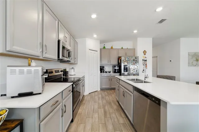 a kitchen with a sink a counter top space stainless steel appliances and cabinets