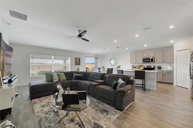 a living room with furniture kitchen view and a wooden floor