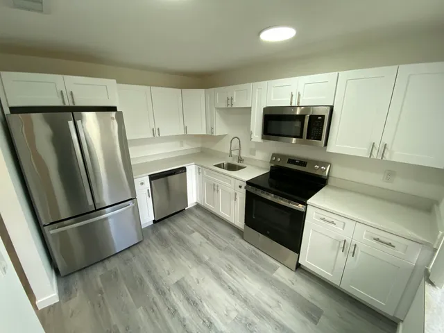 a kitchen with white cabinets sink and stainless steel appliances