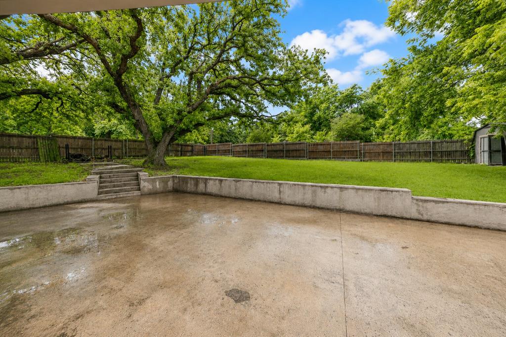 1001 Rosebud Drive Azle, TX 76020 - Photo 30 of 36 Expansive concrete patio area with a retaining wall and steps leading to a tiered lawn