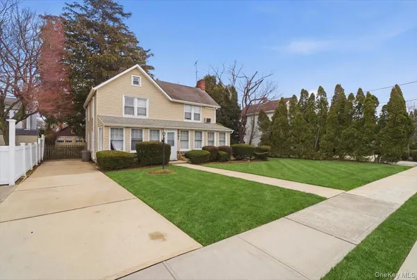 a view of a white house with a big yard and potted plants