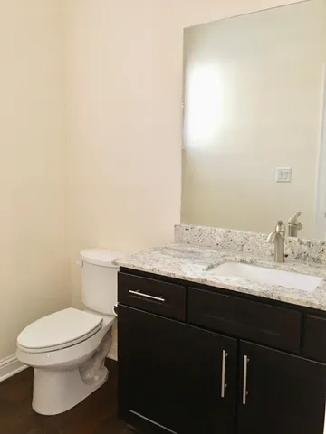 a bathroom with a granite countertop toilet sink and mirror