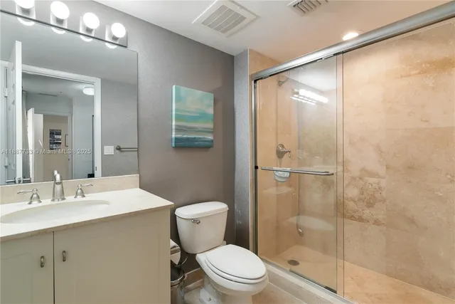 a bathroom with a shower sink vanity mirror and toilet