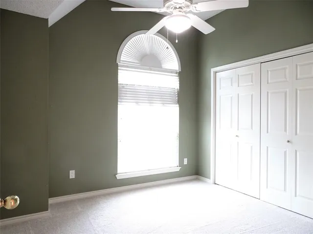 an empty room with a chandelier fan and windows
