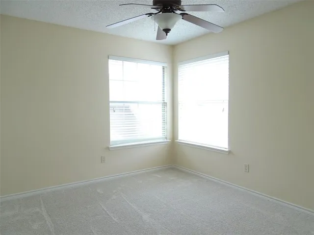 an empty room with a window and a fan
