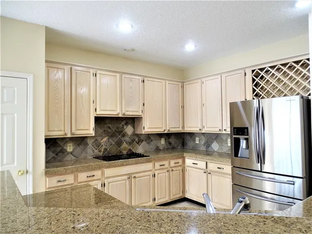 a kitchen with granite countertop a refrigerator sink and white cabinets