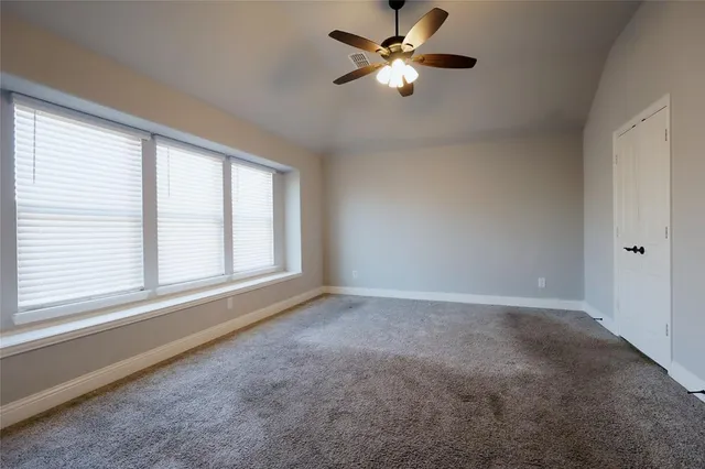 an empty room with chandelier fan and windows