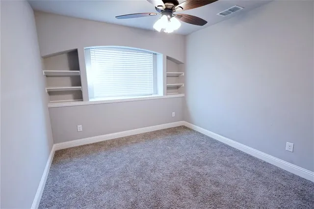 an empty room with a window and a fan