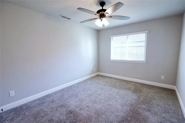 an empty room with a window and a fan