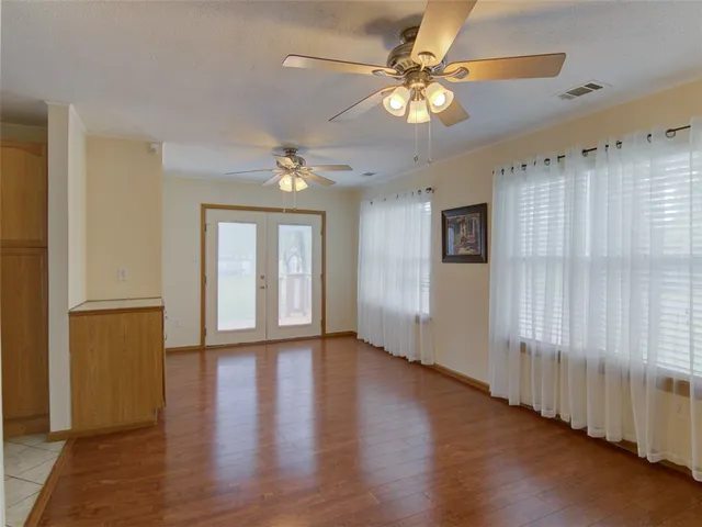 a view of an empty room with wooden floor and fan
