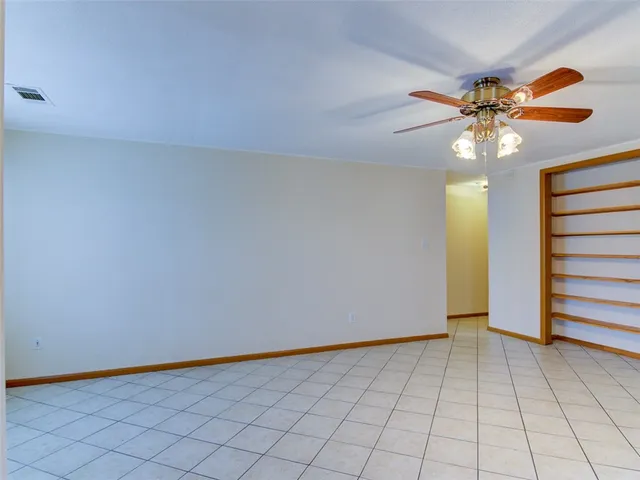 a view of an empty room and chandelier fan