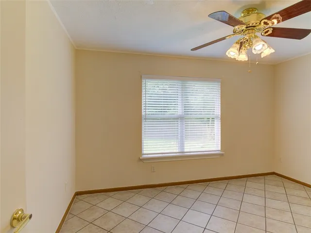 a view of an empty room with window and chandelier fan