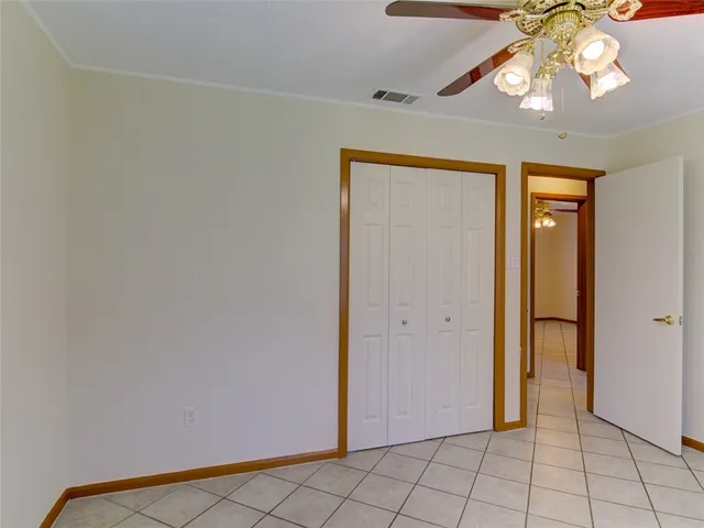 a view of an empty room and chandelier fan