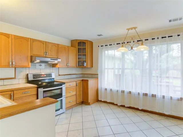 a kitchen with granite countertop a stove a sink and dishwasher wooden cabinets with granite countertops