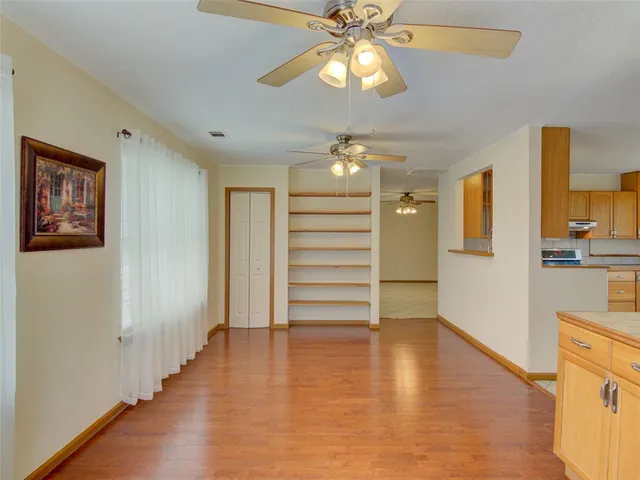wooden floor in an empty room with a chandelier fan