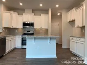 a kitchen with kitchen island granite countertop a sink cabinets and stainless steel appliances