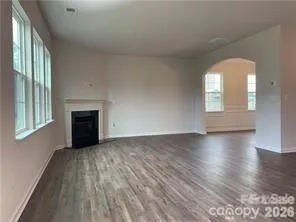 an empty room with wooden floor fireplace and windows