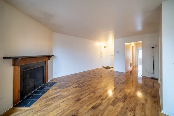 a view of empty room with wooden floor and fireplace