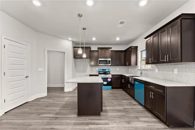 a kitchen with stainless steel appliances kitchen island granite countertop a stove refrigerator and cabinets