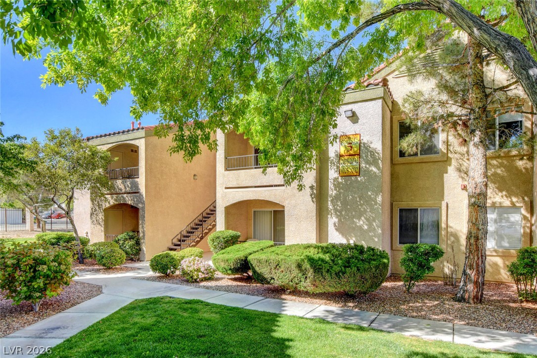 7885 West Flamingo Road, Unit 1050 Las Vegas, NV 89147 - Photo 55 of 62 A terracotta-roofed apartment building with stucco siding is nestled among vibrant green foliage and meticulously maintained landscaping.