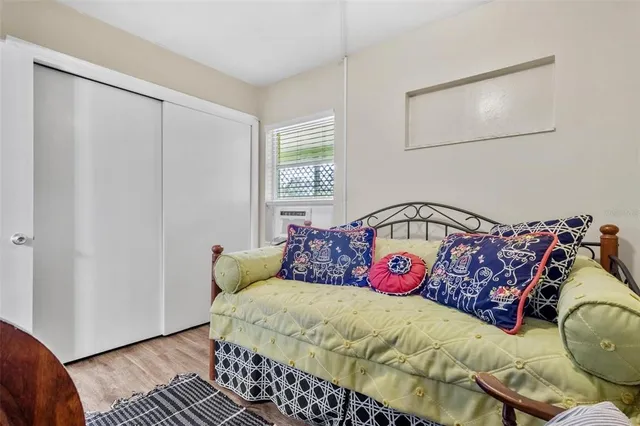 a bed sitting in a bedroom next to a window with a wooden floor