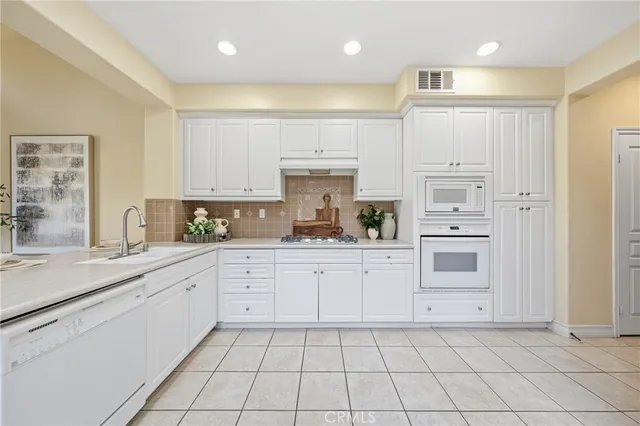 a kitchen with white cabinets appliances and a sink