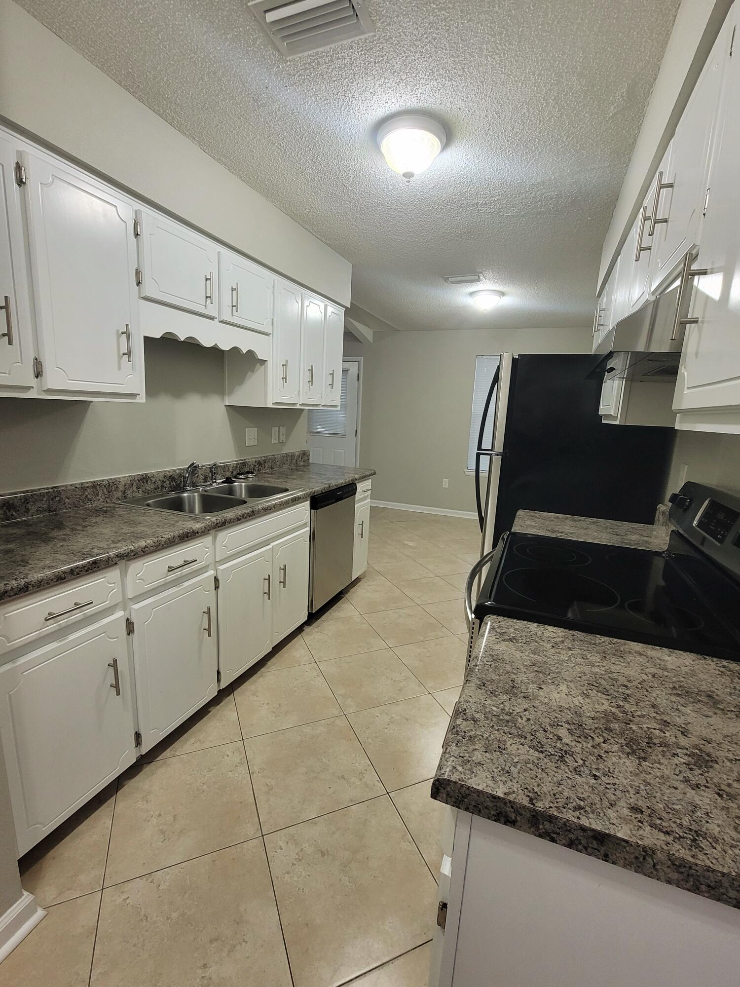 5496 Monterrey Road Crestview, FL 32539 - Photo 5 of 15 a kitchen with kitchen island granite countertop a sink and white cabinets