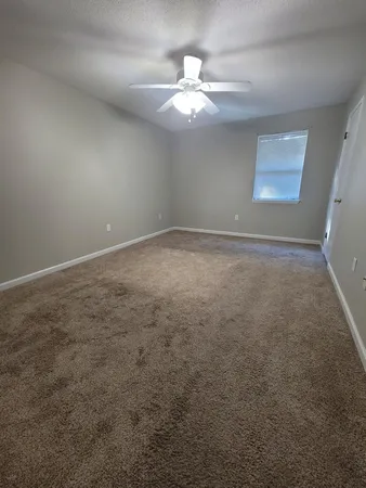 an empty room with a chandelier fan and windows