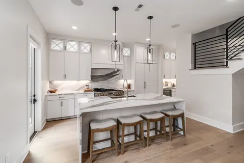 a kitchen with stainless steel appliances granite countertop a stove a sink a refrigerator a kitchen island a dining table and chairs