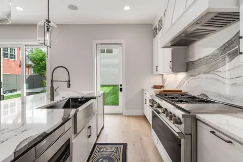 a kitchen with granite countertop a sink a stove and cabinets