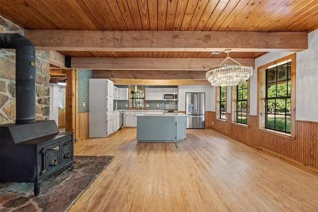 a living room with stainless steel appliances kitchen island granite countertop wooden floors and wide window