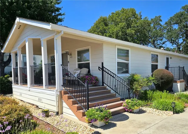 a view of a house with a small yard plants and large tree
