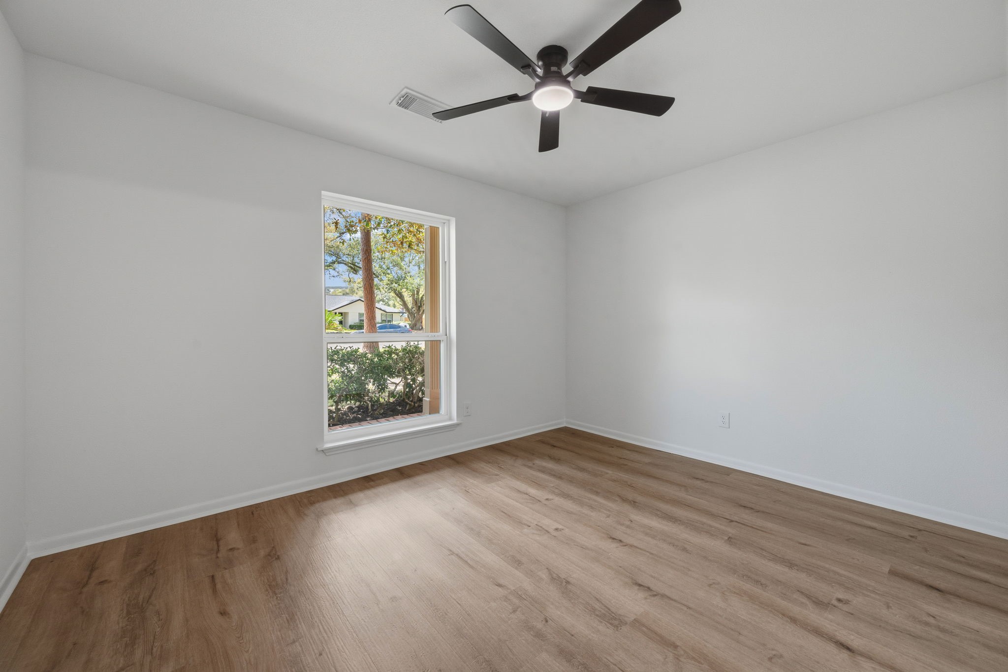210 Ridgemont Drive Alvin, TX 77511 - Photo 15 of 27 This room features a clean, modern design with light wood flooring and white walls. A large window provides natural light, and a ceiling fan enhances comfort. Ideal for a bedroom or office space.