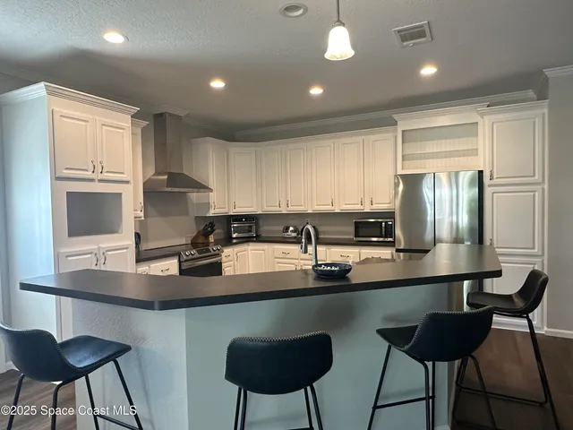 a kitchen with stainless steel appliances granite countertop a sink a stove a refrigerator cabinets and chairs