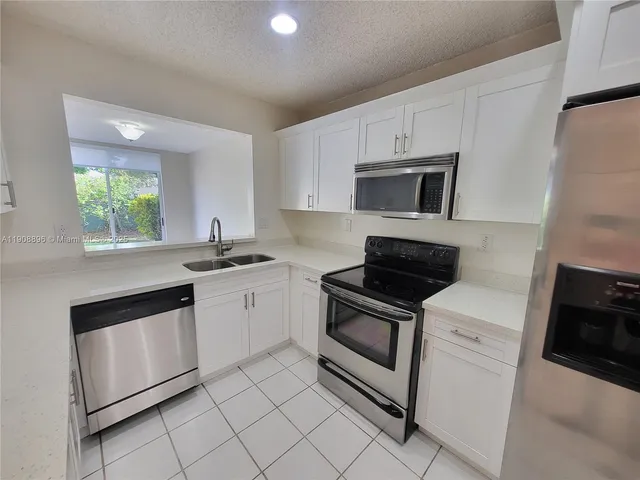 a kitchen with a refrigerator sink and cabinets