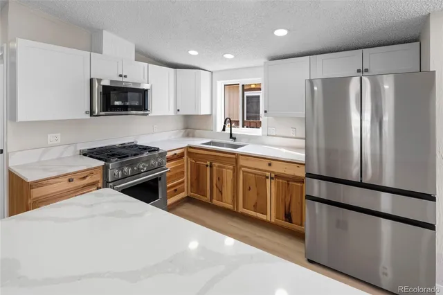 a kitchen with stainless steel appliances granite countertop a refrigerator stove a sink and a microwave