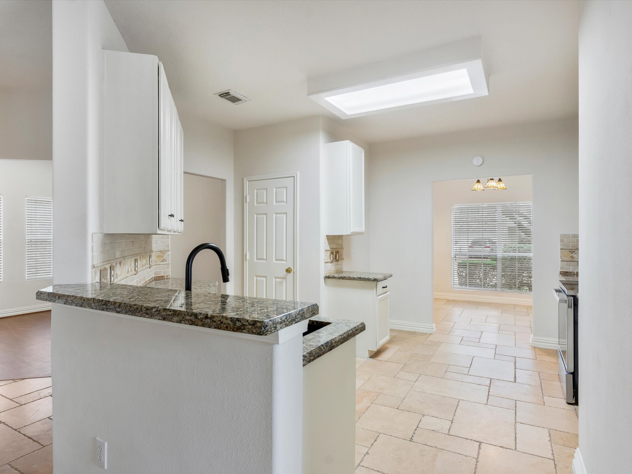 19422 Harvest Stream Way Houston, TX 77084 - Photo 10 of 41 This kitchen features a modern design with granite countertops, white cabinetry, and tile flooring. It has a bright, open layout with ample natural light from large windows, and a convenient pass-through to the breakfast and dining rooms.