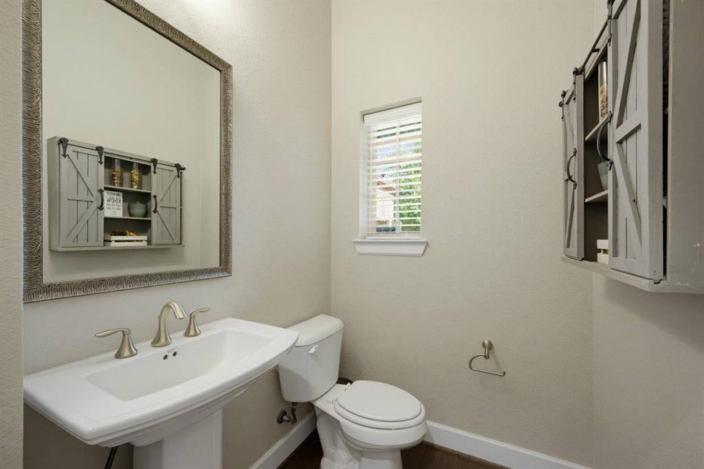 2721 Old Shire Path Road Prosper, TX 75078 - Photo 14 of 39 Pedestal sink with brushed nickel faucet, framed mirror, and a wall-mounted barn door style cabinet