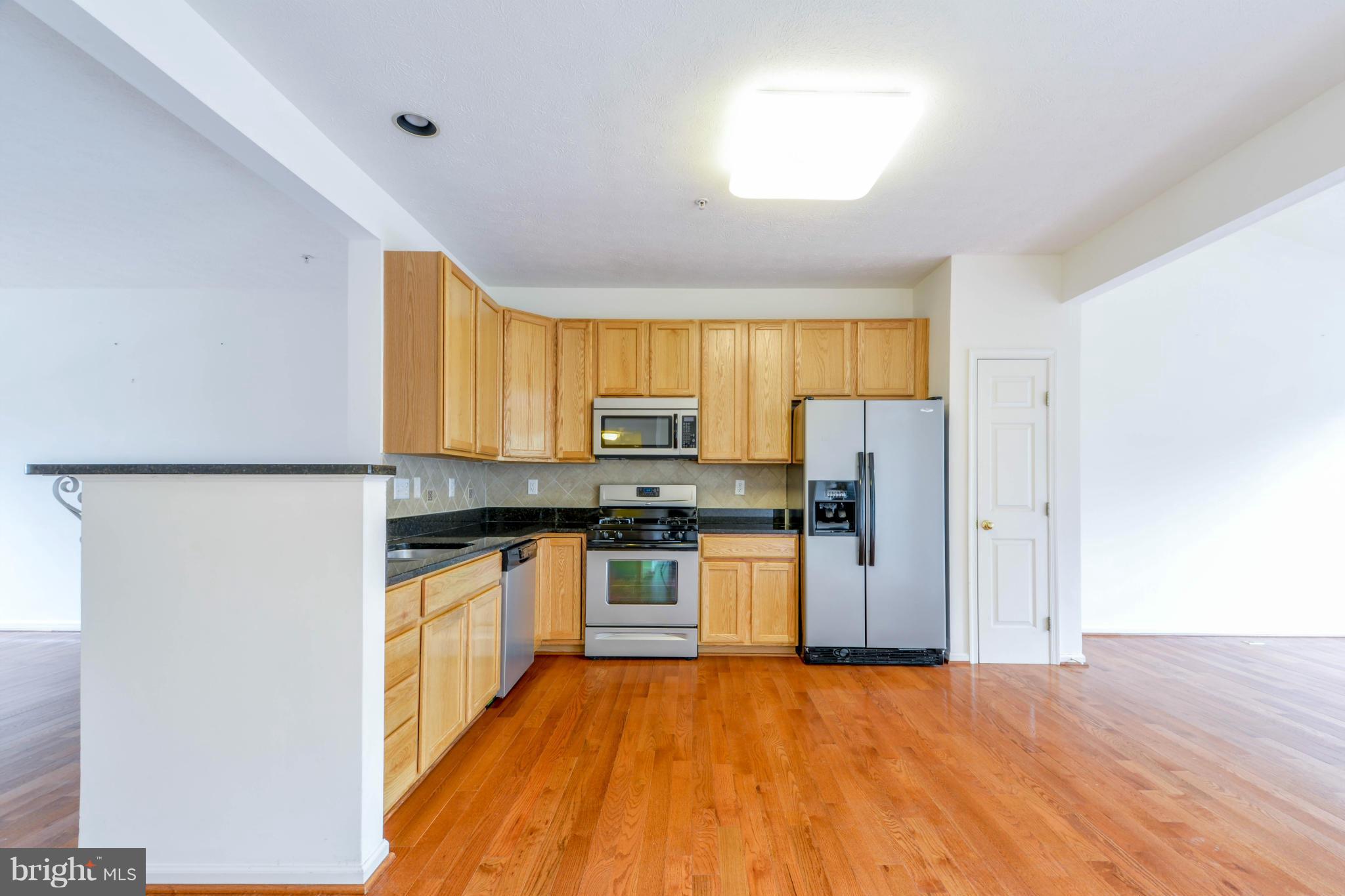 1447 Pangbourne Way Hanover, MD 21076 - Photo 11 of 30 a kitchen with granite countertop a refrigerator and a stove top oven